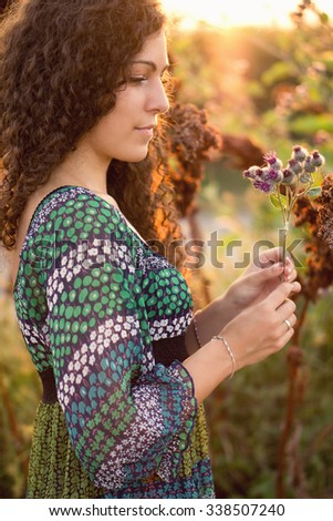 Young brunette woman is taking flowers. Color effects, custom white balance used on this picture.
