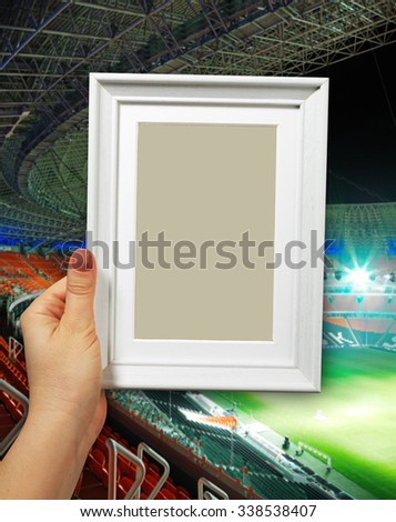 Wooden frame in beautiful woman hands. football stadium on the background
