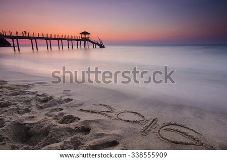 2016 word written on sand and Silhouette of fisherman cottage during sunrise