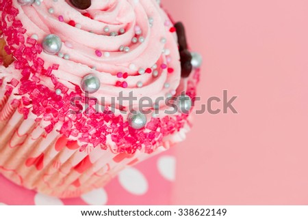 Birthday or wedding cupcake with strawberry icing on pink background.