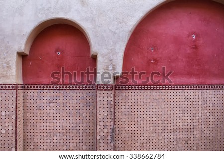 Traditional Architecture Details, Morocco Part of a facade with arcs, traditional in arabian architecture. Partly painted red, partly with tiles detail.