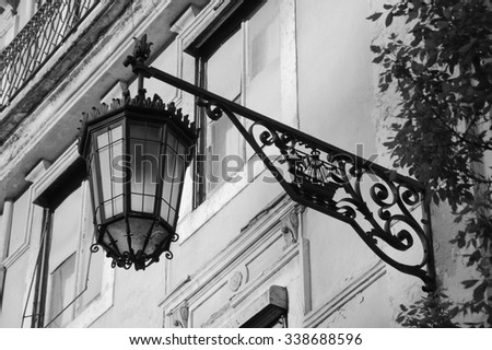 Lantern with Lisbon symbol (ship with two ravens) on the old building in the centre of Lisbon (Portugal). Aged photo. Black and white.