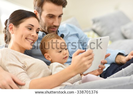 Parents with baby girl in sofa using digital tablet