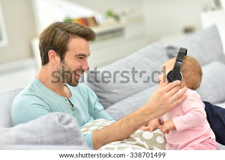 Daddy and baby girl in sofa using tablet and headphones