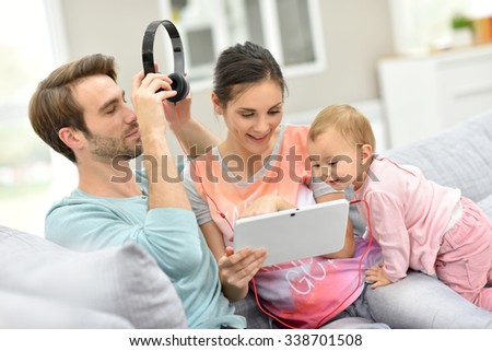Couple with baby  in sofa watching movie on tablet