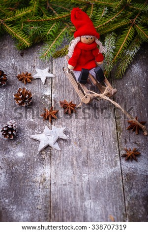 Xmas or new year composition with holiday decoration - sledge, little man figures and fir branches, pine cones on wooden background. Xmas card. Space for text