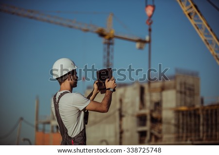 Construction engineer with the tablet pictures of objects on a construction site