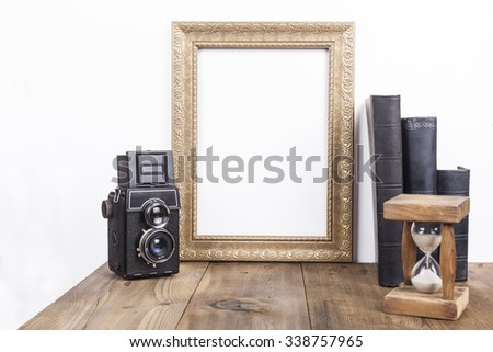 Vertical Golden Empty Frame With Old Books And Old Camera on Brown Wood Table