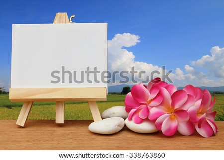 canvas frame and pink plumeria on paddy field in cloudy day background