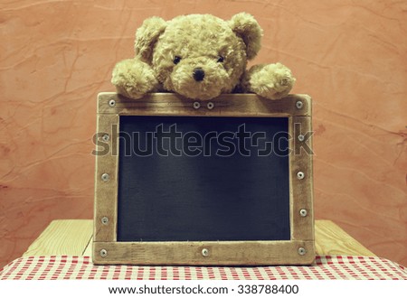 teddy bear with empty blackboard. put on fabric red, white. background brick color. vintage and retro style.