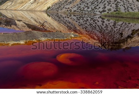 Red artificial lake and hills as a result of mining and production of copper