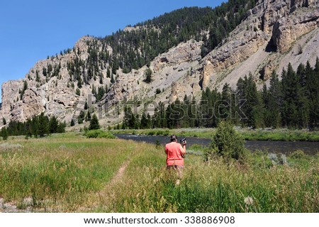 Tourist stops to snap a picture of the Gallatin Mountains and Gallatin River in Montana.  Trail leads toward river.