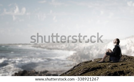 Thoughtful young businesswoman sitting alone on rock top