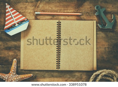 top view image of open blank notebook, wooden sailboat, nautical rope. travel and adventure concept. retro filtered image 