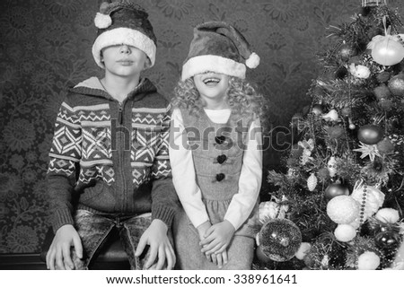 Retro image of funny kids with Santa hats at Christmas holiday near decorated christmas tree. New Year. Concept of family celebration. Retro revival, old edition, black and white