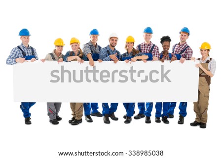 Portrait of happy construction workers holding blank billboard against white background