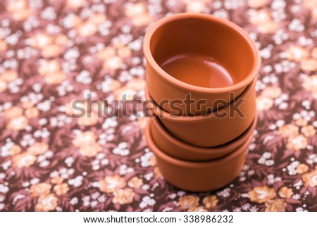Beautiful terracotta colored empty tough pottery dishes kitchen utensil for salad in stack top view indoor on floral background, horizontal picture