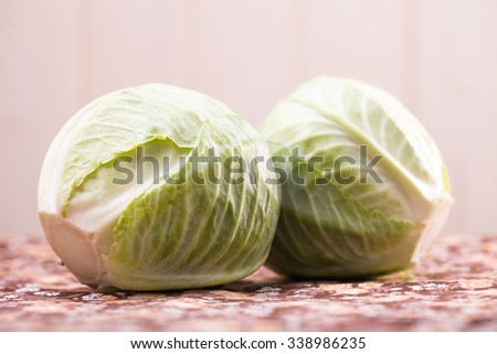 Two ripe fresh heads of white cabbage green vegetable rich with vitamins laying on table harvest in autumn on blur light background indoor closeup, horizontal picture