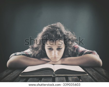 Teenager reading a book on the table.