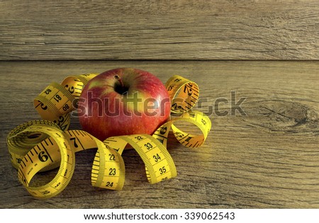 Measuring tape wrapped around a red apple as a symbol of diet