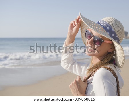 happy fashion blonde girl smiling portrait in the beach, wearing hat, a bag, shorts and white shirt, in the beach, profile photo