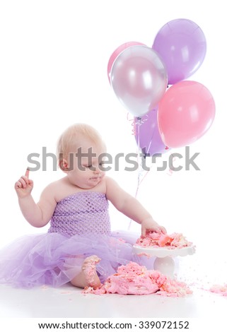 Adorable baby girl eating a birthday cake.  Isolated on white.