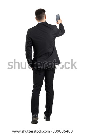 Businessman in suit searching for good phone signal rear view or taking photo. Full body length portrait isolated over white studio background. 