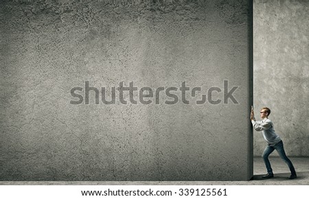 Teenager boy pushing stone blank wall. Place for text