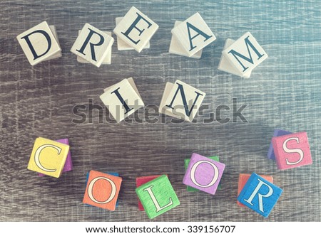 Dream In Colors. Motivational message written with colorful wooden blocks. Cross processed image for vintage look