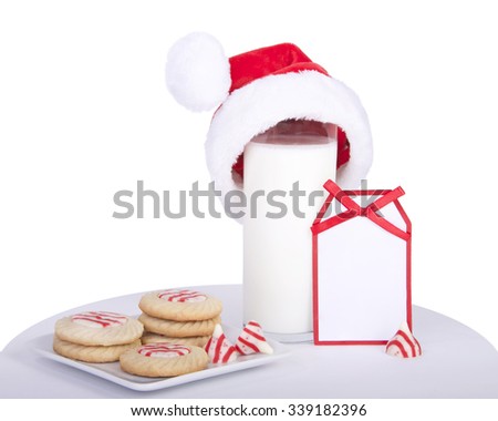 candy cane stripped peppermint flavor sugar cookies on a square plate with a glass of milk wearing a miniature santa hat. Note card next to milk blank for your message