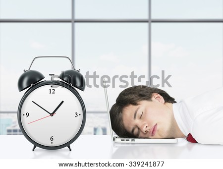 Relaxing professional on the laptop in the panoramic office. An alarm clock is on foreground. Royalty-Free Stock Photo #339241877