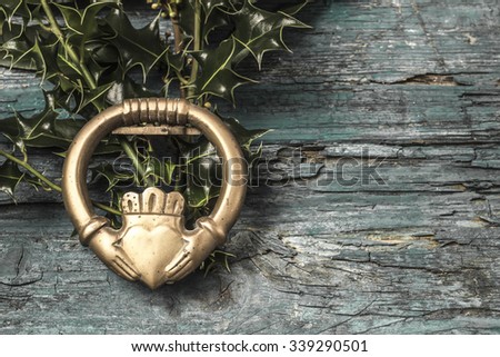 Claddagh and holly branches  irish symbol of love, friendship and loyalty in old wooden background Royalty-Free Stock Photo #339290501