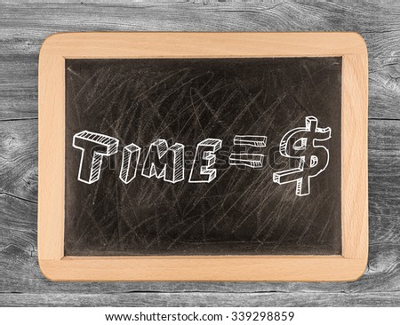 "Time is money" handwritten with white chalk on a blackboard