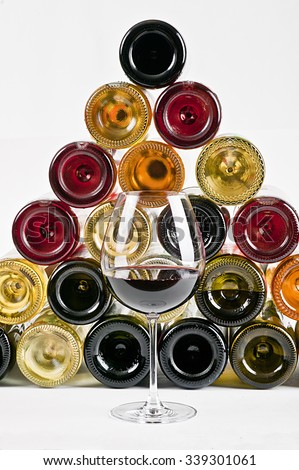 a glass of red wine and wine bottles on background