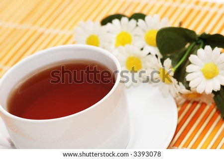 Cup of tea and camomiles at  the background