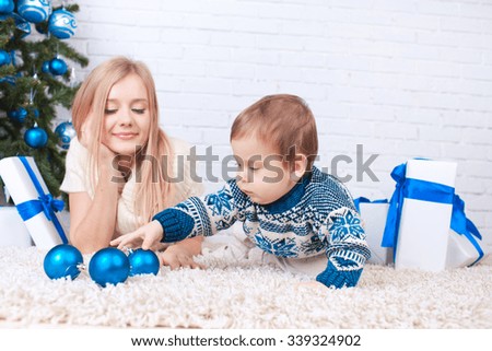 Mother with son holding presents near christmas tree