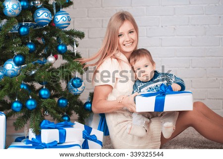 Mother with son holding presents near christmas tree