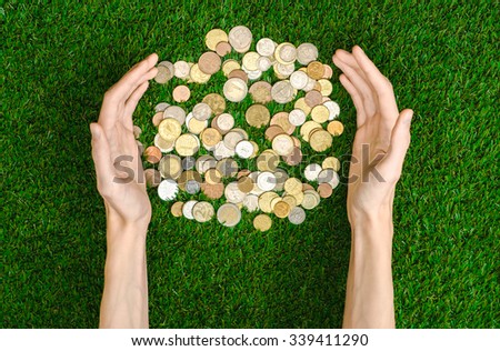 Money and Finance Topic: Money coins and human hand showing gesture on a background of green grass top view