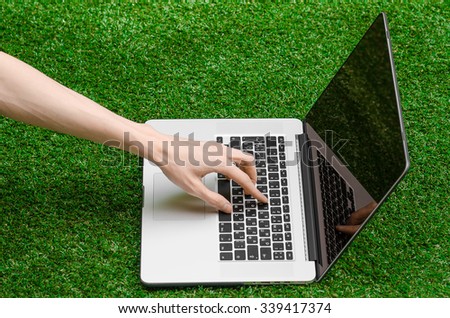 Work outdoors theme: the human hand shows gestures and an open notebook on a background of green grass