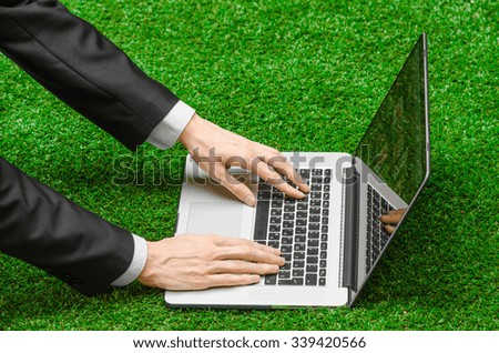 Work outdoors and businessman topic: human hands show the gestures in a black suit and an open notebook on a background of green grass