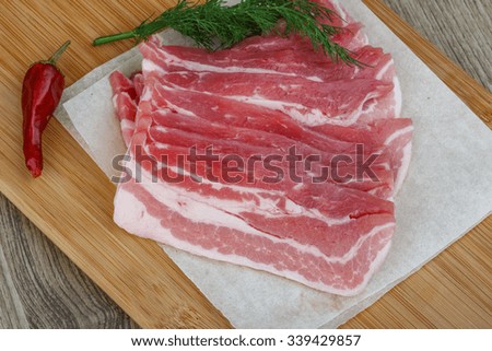 Raw bacon on the wood board with dill leaves