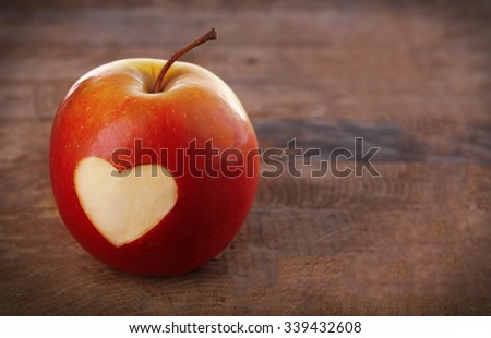 Apple with heart on wooden table