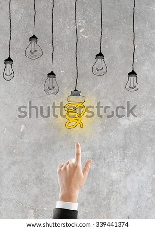 Man hand with glowing lightbulb at concrete background