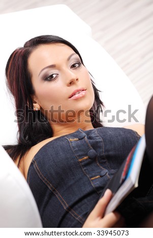 Young woman relaxing in a sofa and reading newspaper
