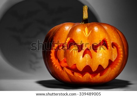 Scary Halloween pumpkin resembling a Chinese dragon head, with an ominous shadow with bats