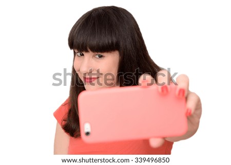 Pretty girl taking a selfie using her smartphone, isolated on white background.
