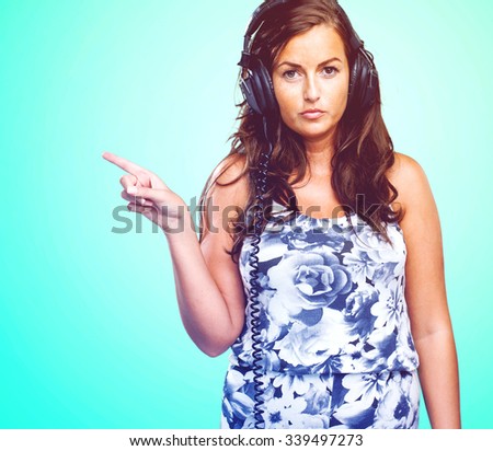 serious woman listening to music and pointing to the copy space
