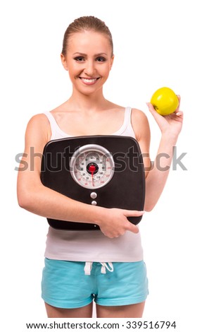 Portrait of a young happy girl holding apple and weight, isolated on a white background