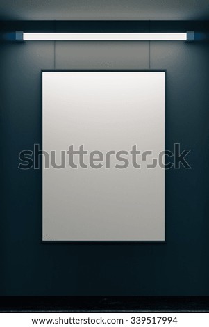 Blank picture frame on grey wall with glowing lamp, mock up