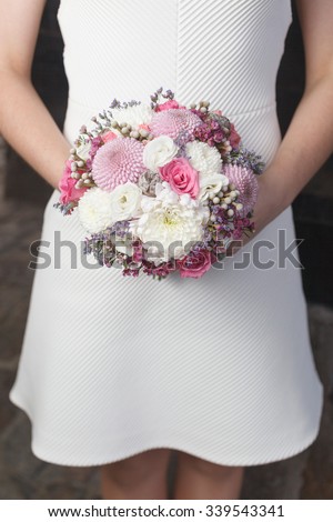 White and pink wedding bouquet in the hands of the bride